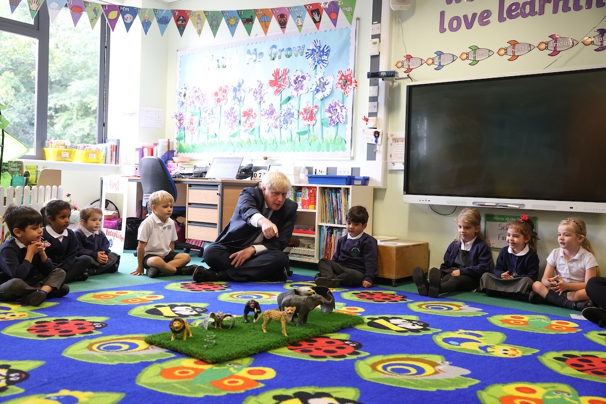 Boris Johnson sits on a classroom floor with some Beechfield pupils